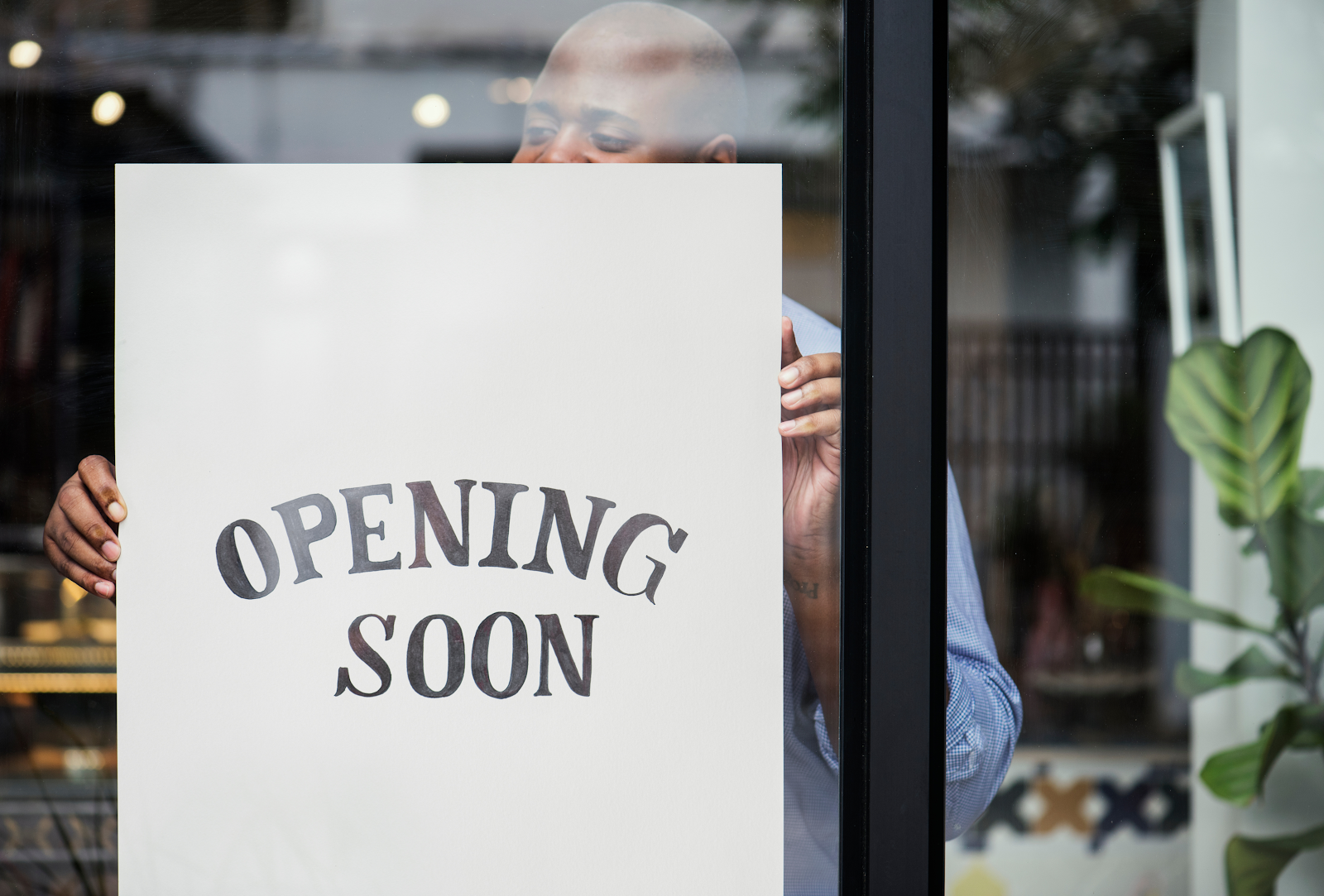 A restaurant owner places an "Opening Soon" sign in the window