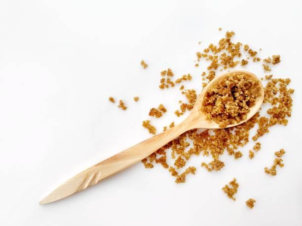 Wooden spoon with grains on top on white background