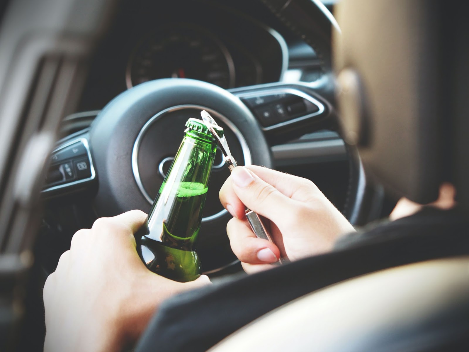 A driver opening a bottle of beer while driving 
