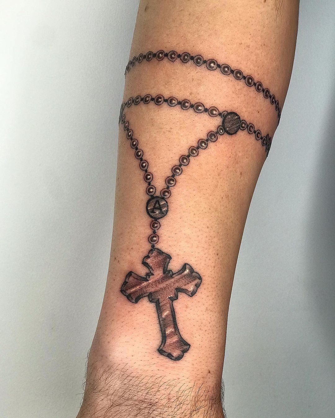 forearm rosary tattoo on arm