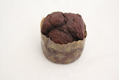 a close-up of one chocolate muffin in a paper liner