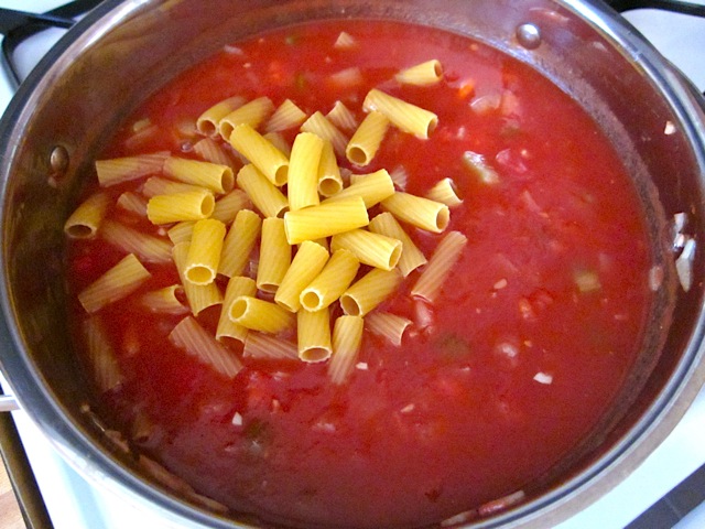pasta being added to sauce in pot 