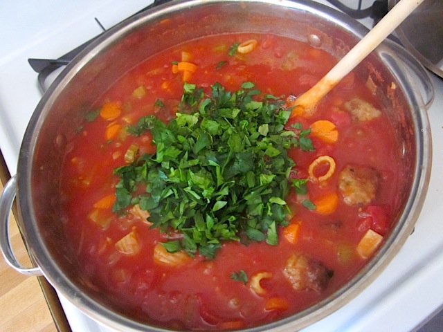 chopped parsley added to soup in pot 
