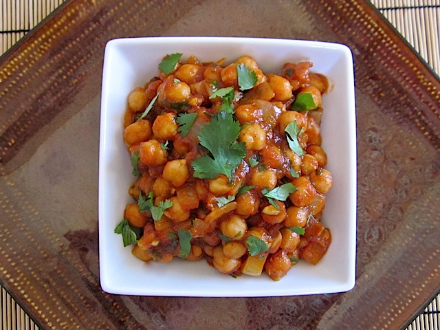 curried chick peas in white bowl garnished with cilantro 