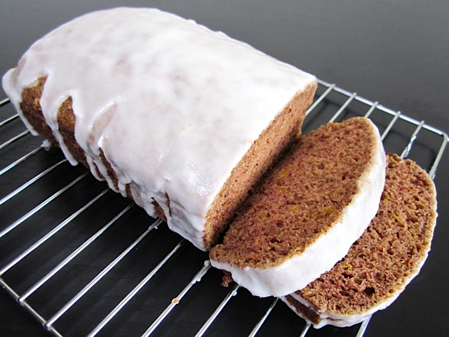 loaf of lemon spice cake on cooling rack with two slices cut off