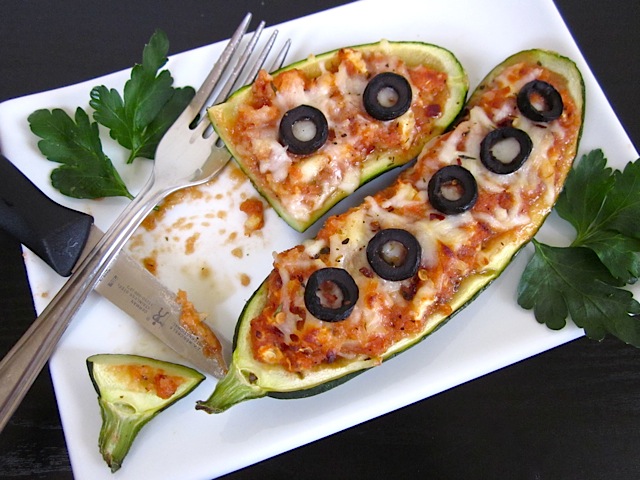 stuffed zucchini pizzas on plate with fork and bite taken out 