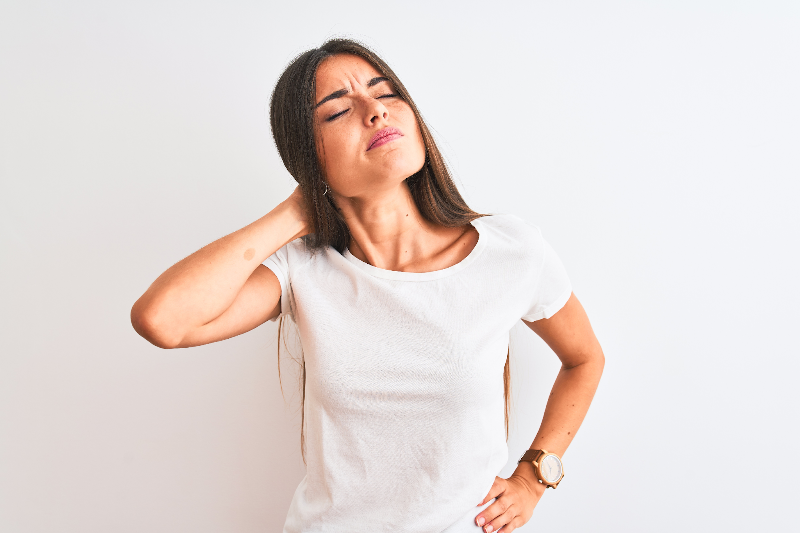 mulher com a mão repousada na região cervical com expressão de dor 