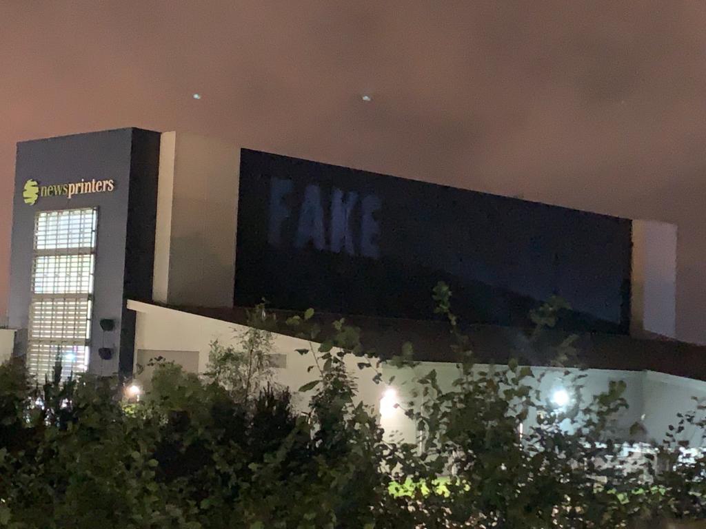 the word fake is being projected onto the building of the Newsprinters