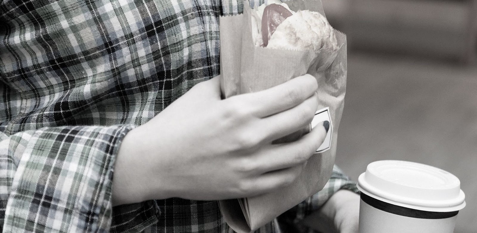 person holding a burger and a take-away coffee