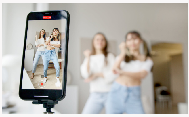 Two young women recording themselves doing a dance.