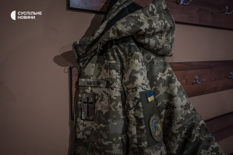 Зимова куртка капелана ЗСУ з офіційними шевронами військового капеланства очікує на пастора Євгена, поки він обідає, грудень 2022 року.