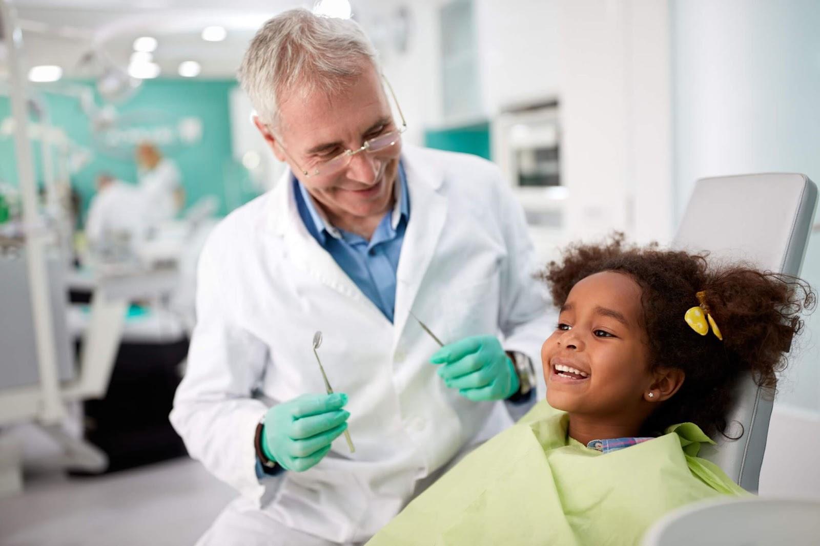 criança sorrindo ao lado de seu dentista durante uma consulta odontológica