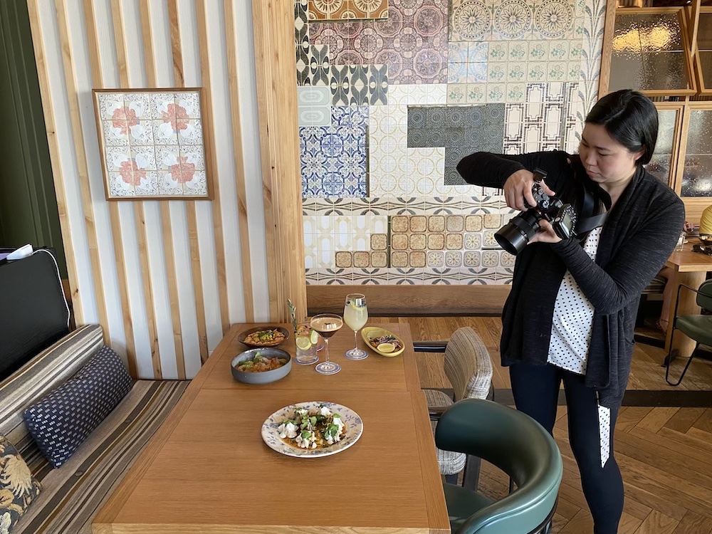 Behind the scenes portrait of photographer Nicole Loeb reviewing images on her camera at restaurant.