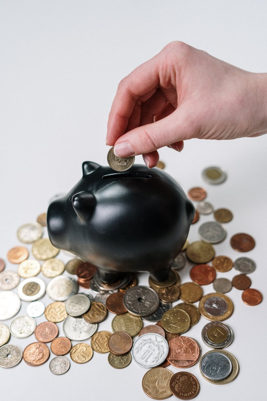 putting coin in black piggy bank - saving money
