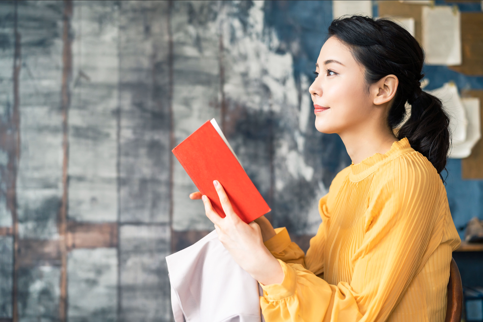 Yellow shirt woman is trying to memorise Hiragana characters in the red book.