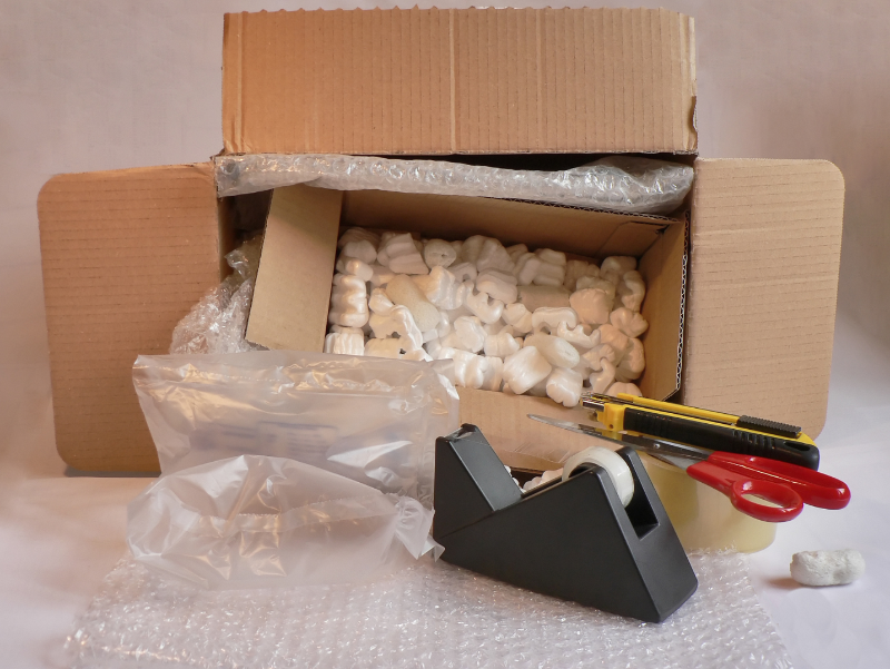 Picture of packing materials: tape, plastic and bubble wrap, boxes, and styrofoam.