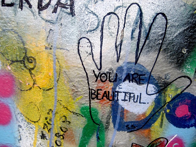 Graffiti covering a wall, including the outline of a hand, in which is written, "You are beautiful." When you practice self-care, that's a huge guilt complex antidote.