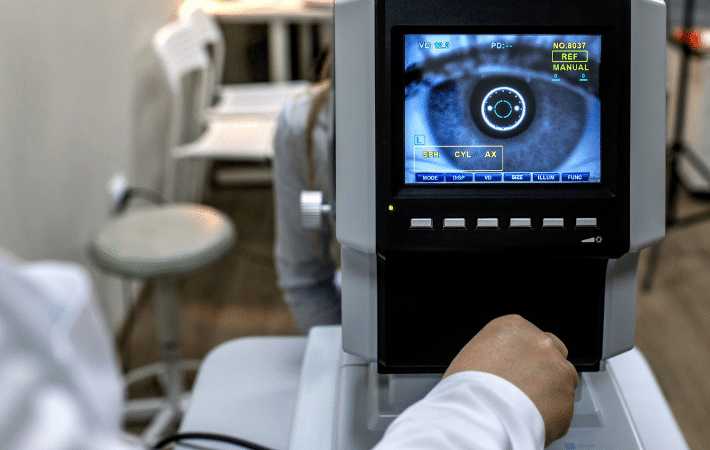 An optometrist using a digital imaging machine to observe a patient’s eye