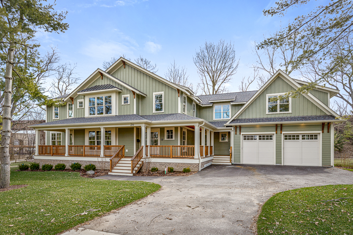 Sprawling two-story home with sage board-and-batten siding with a cedar wrap around front porch. 