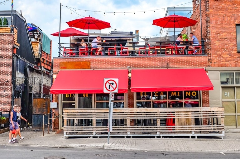 bar building with red awning and upper patio with umbrellas and chairs 