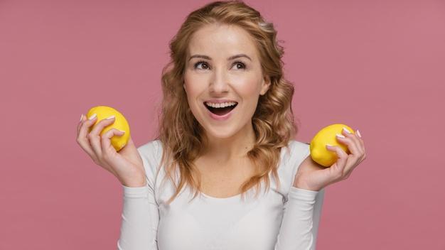 Woman laughing holding lemons Free Photo