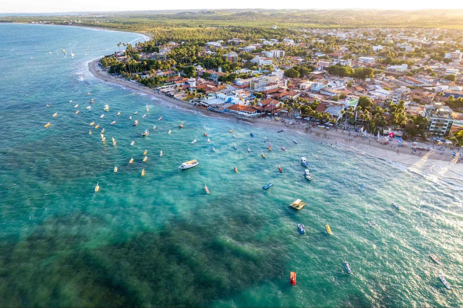 Orla da praia de Porto de Galinhas, em Perbambuco, com barcos parados próximos à areia.