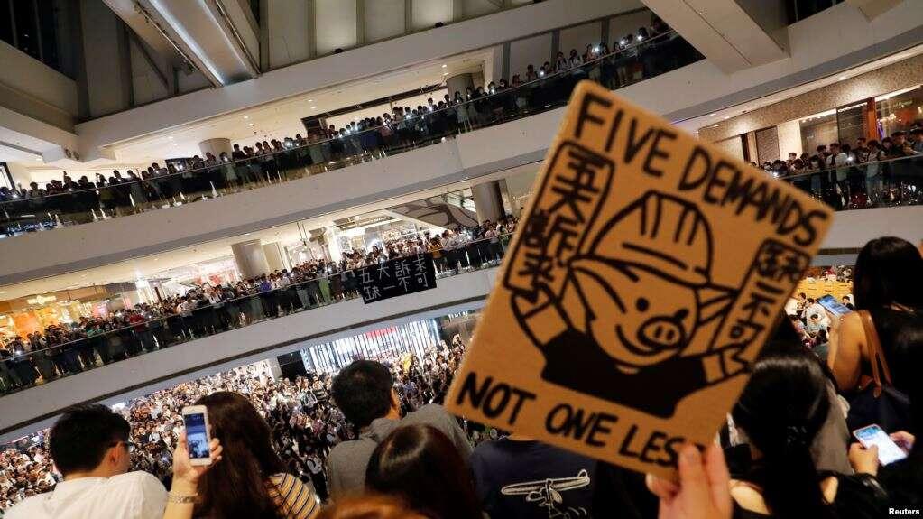 香港抗议者在中环国际金融中心手举“五项诉求,缺一不可”的标语牌大合唱《愿荣光归香港》。