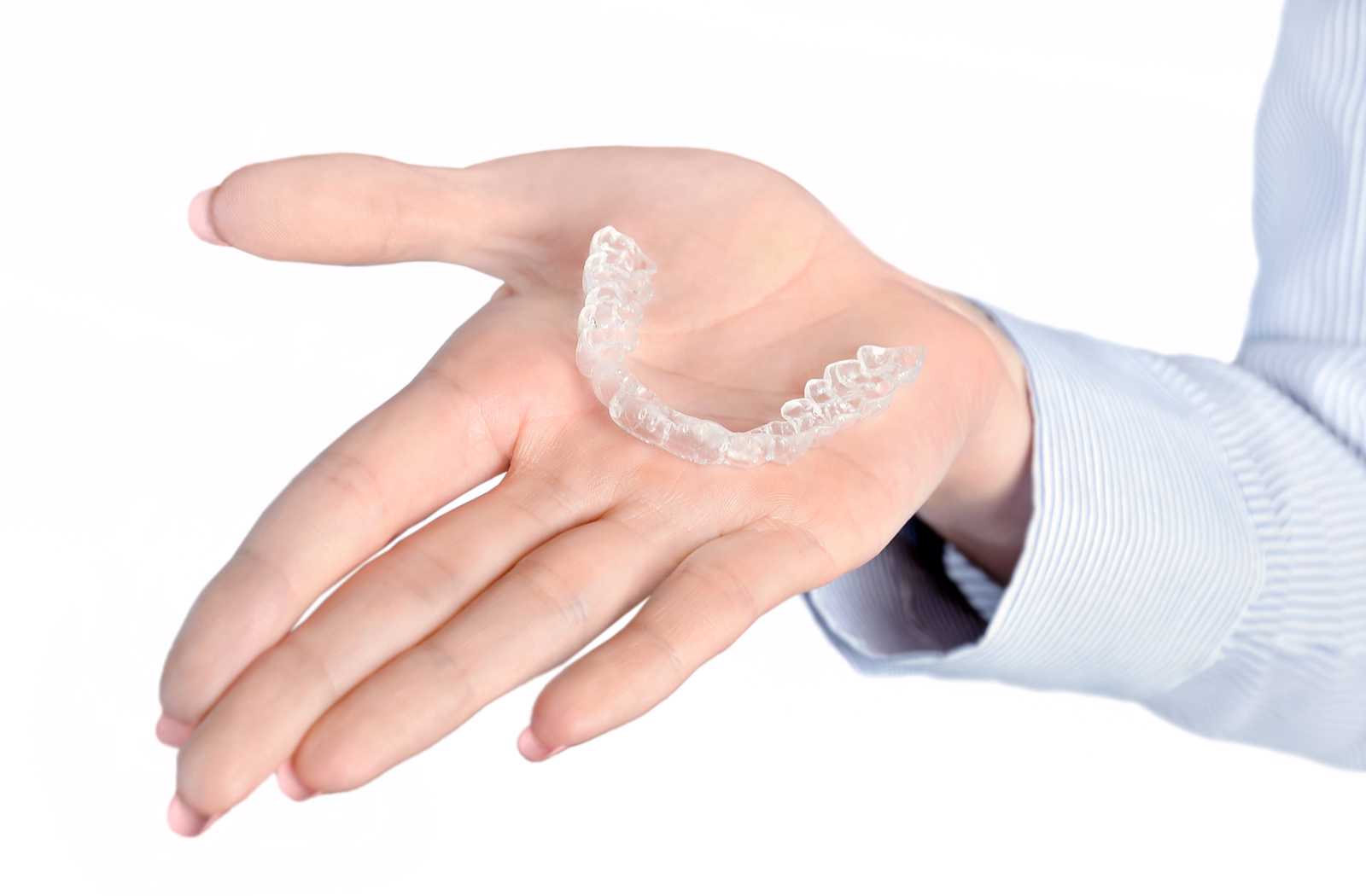 hand on white background holding out clear dental nightguard