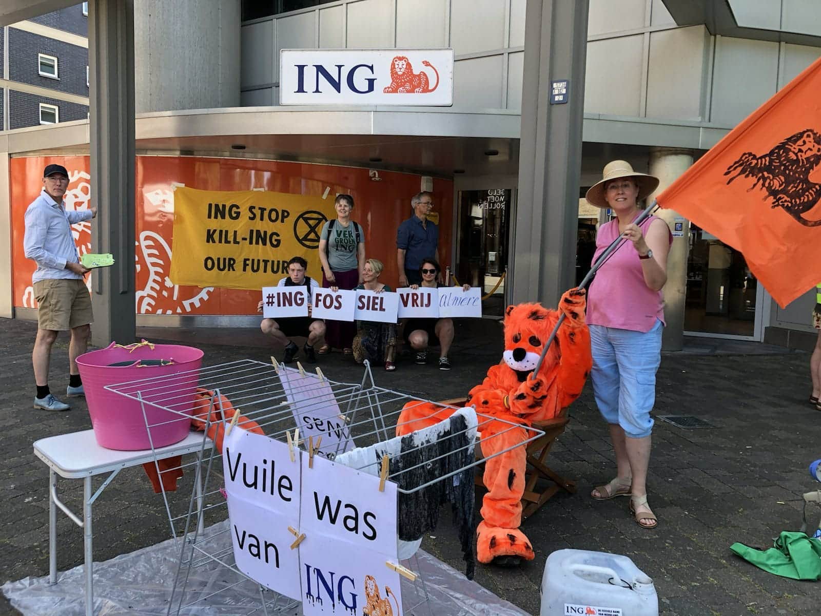 Rebels rally outside an ING bank branch with a washing rack and a tiger soft toy