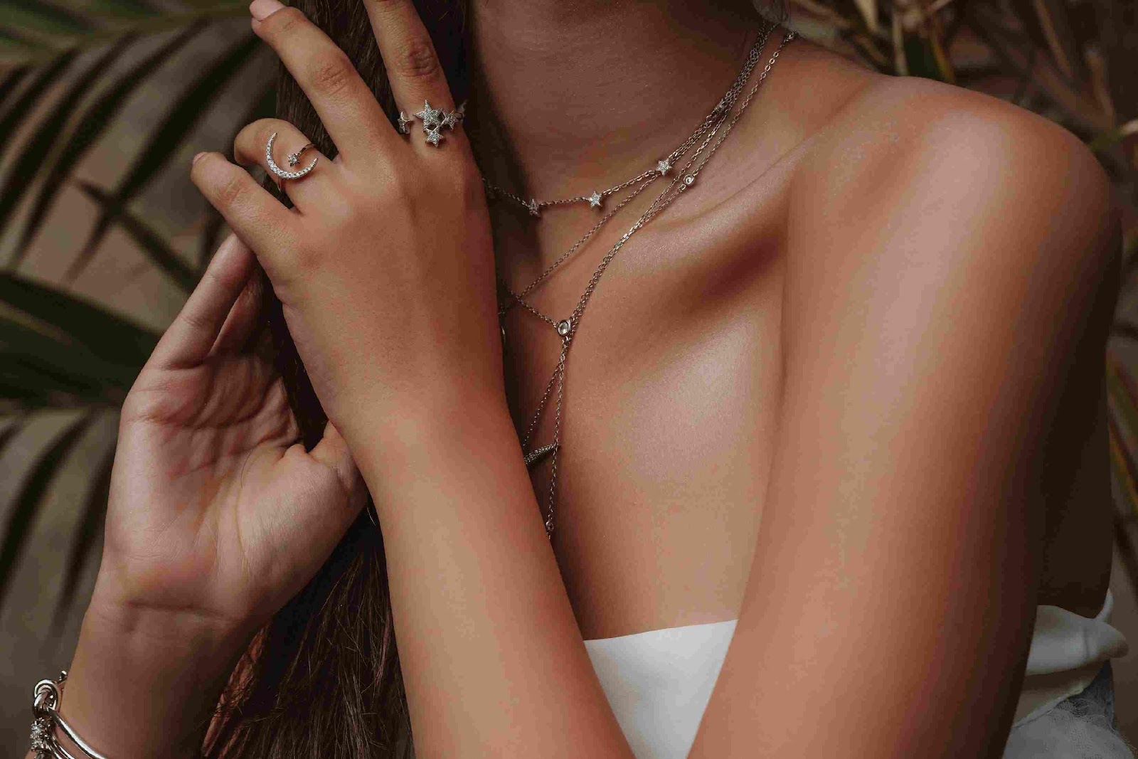A person wearing a necklace and ring

Description automatically generated