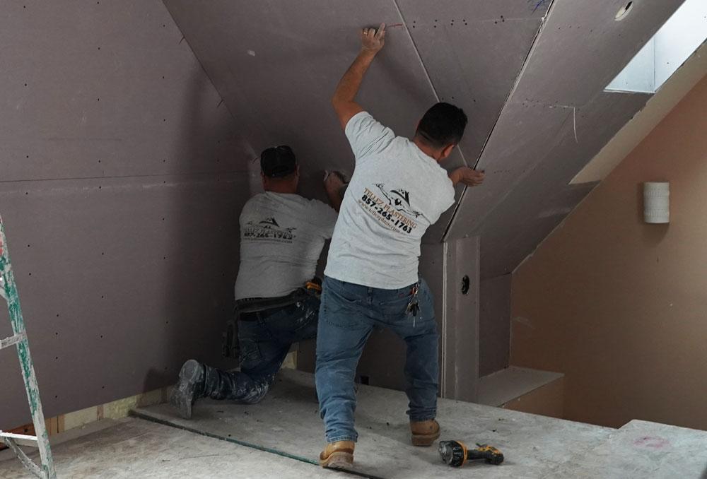 Two contractors working on drywall.