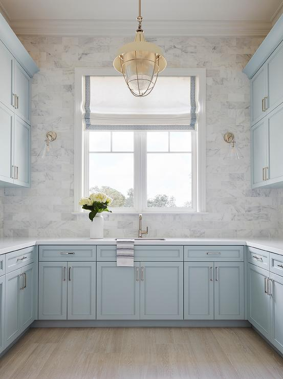 pastel blue shaker cabinets with light wood floors and grey tile backsplash