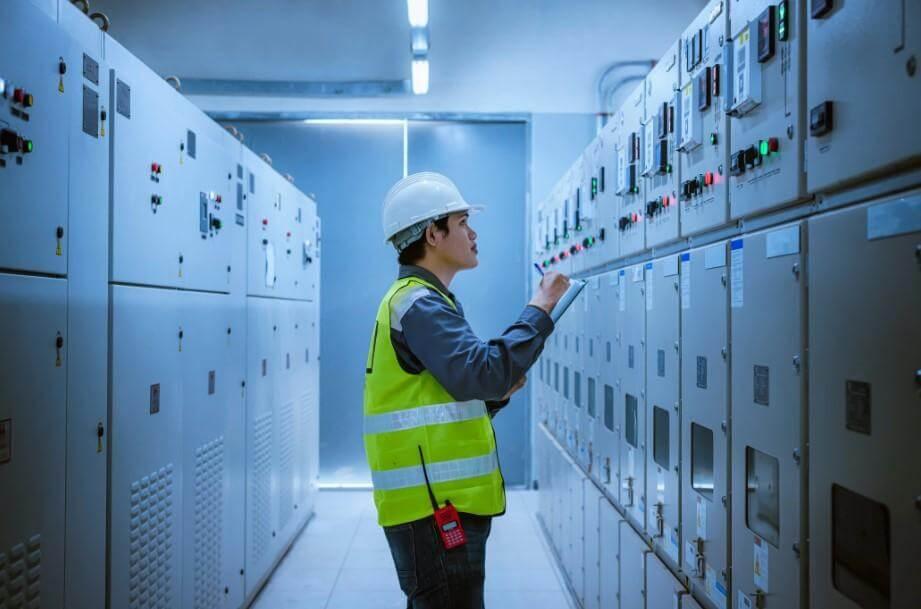 Funcionário analisando quadros elétricos industriais