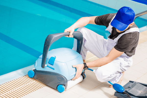 person performing pool maintenance, holding a pool vacuum