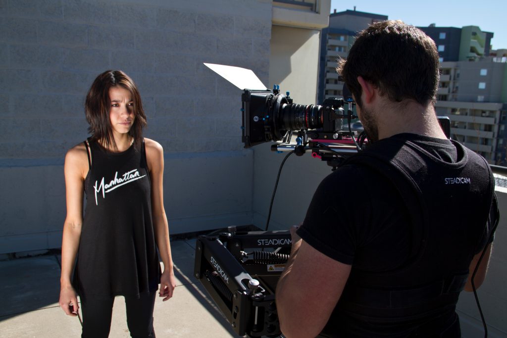 An actress stands in front of a camera on set.