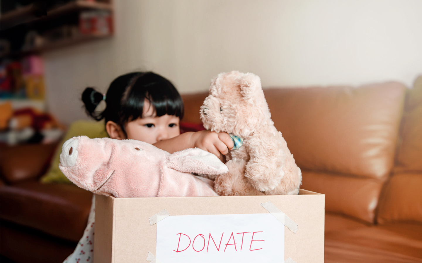kid putting fluffy toy in donation box