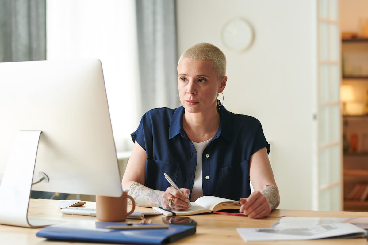 Working while on leave of absence: entrepreneur looking at a computer while writing on a notebook