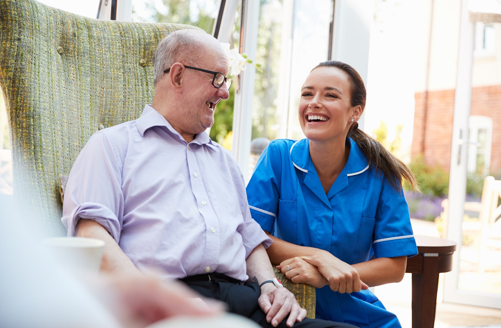 A female nurse laughing with a male memory care patient
