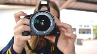 a-woman-holding-a-camera-in-her-hand-and-clicking-photo-of-someone