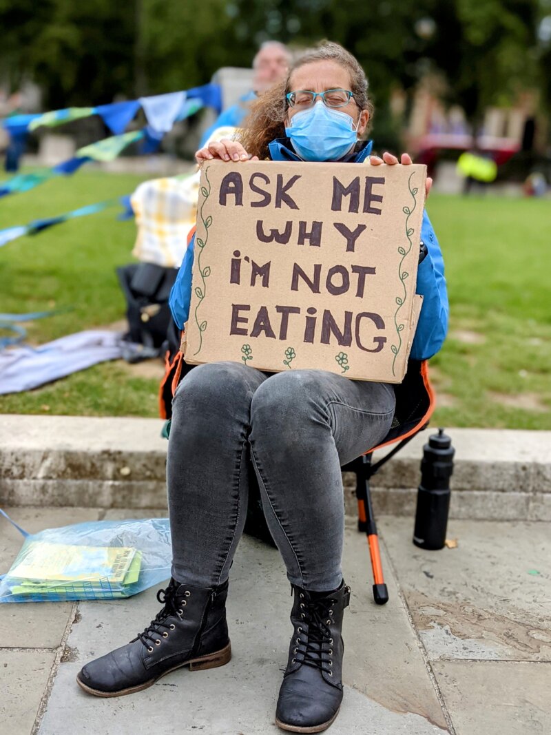 A rebel holding a sign 'ask me why I'm not eating'