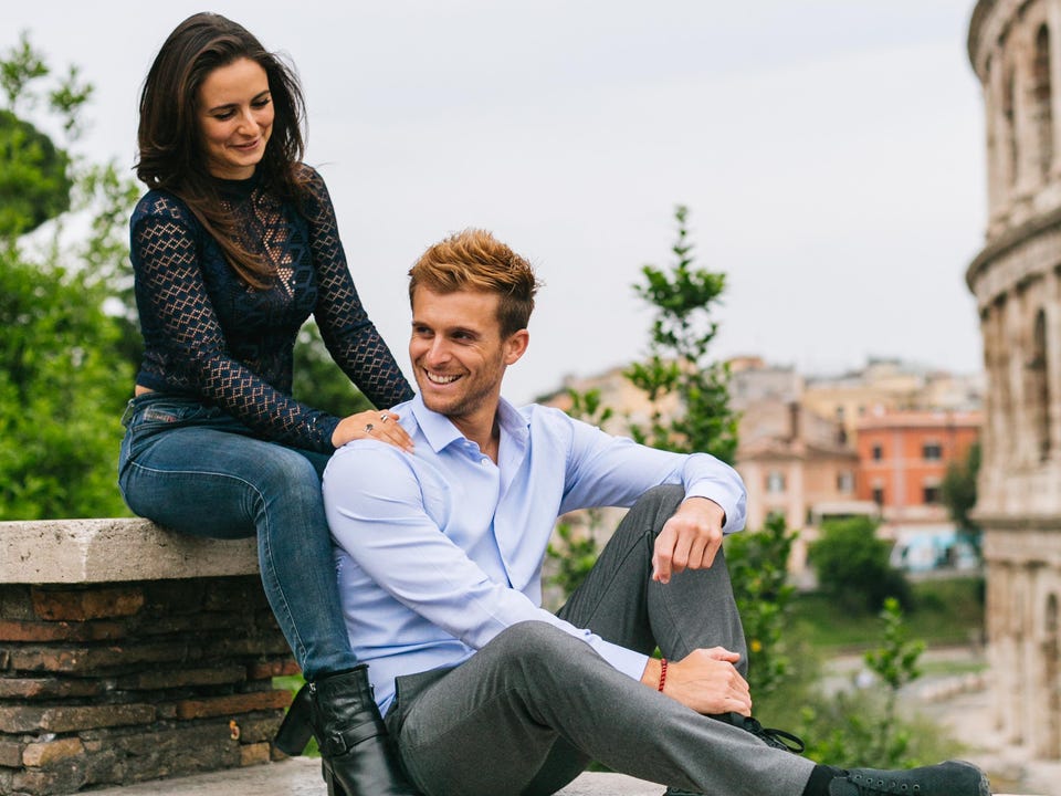 attractive man and woman entrepreneurs, couple sitting in front of colosseum in rome
