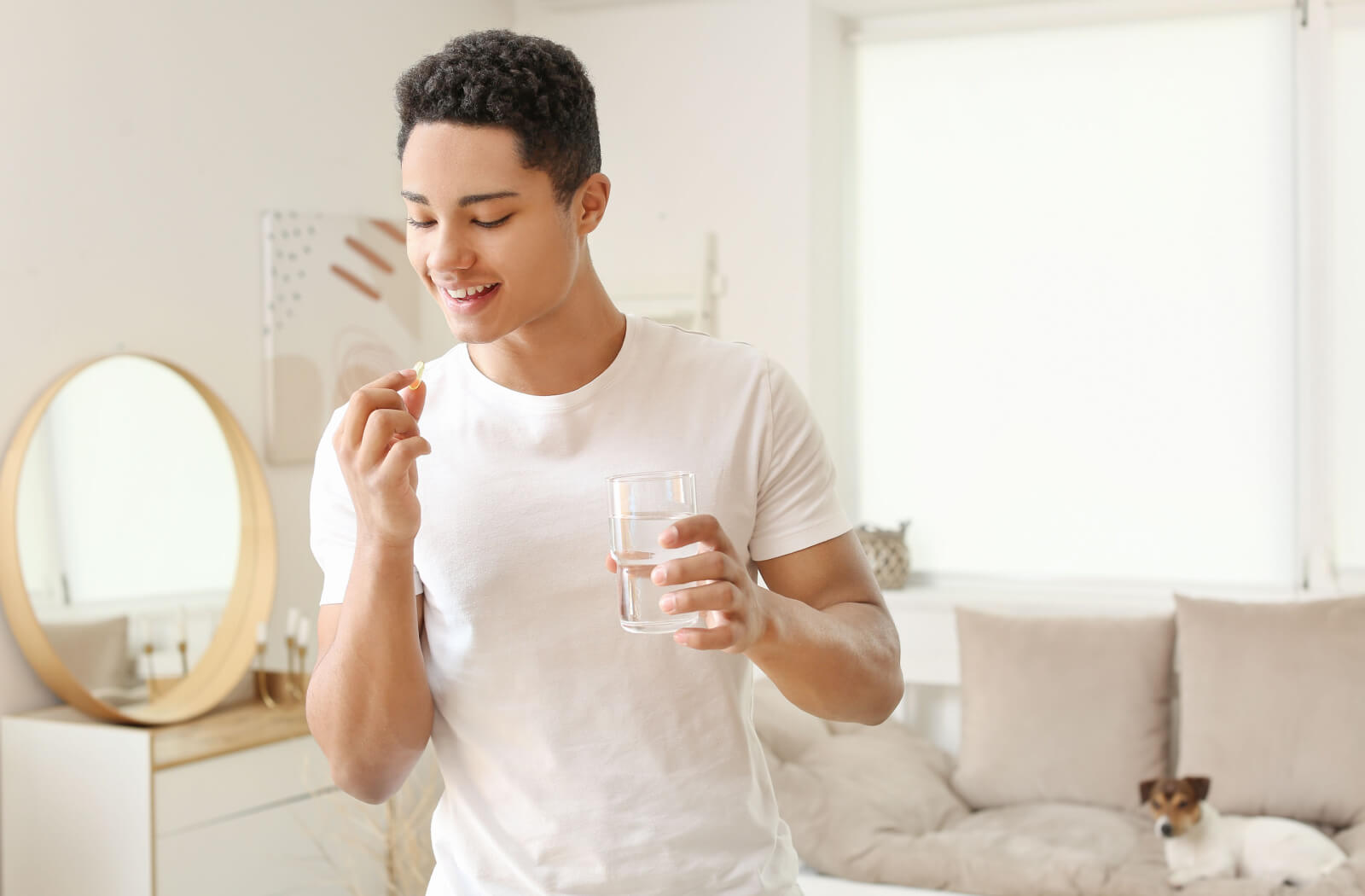 A teenage boy in a white shirt about to take vitamin supplements.