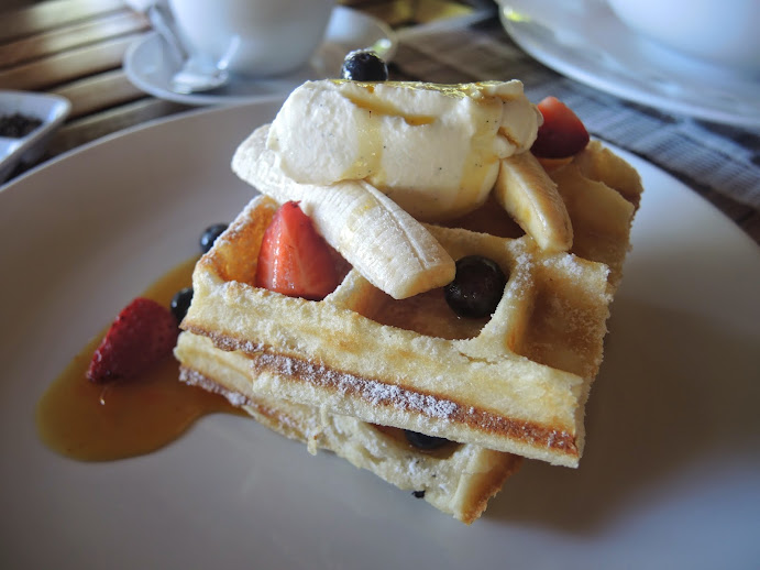 a plate of waffles with fruit and syrup