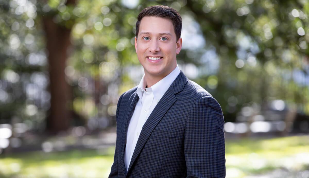 A person in a suit smiling  Description automatically generated with low confidence