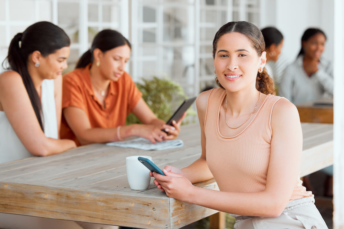 Health outcomes: woman smiling at the camera while holding her phone