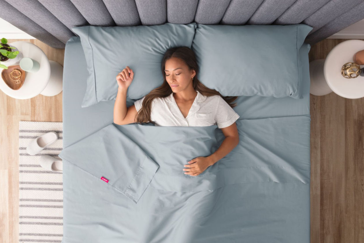 Woman sleeping under light blue sheets