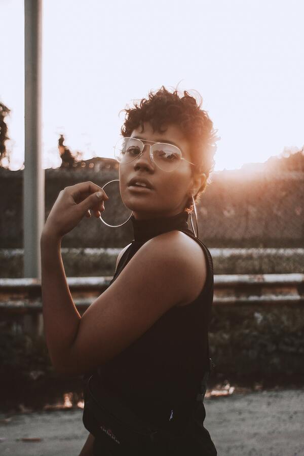 Foto de uma mulher negra posando com um por-do-sol ao fundo 