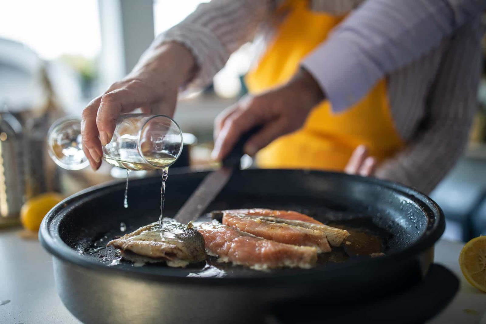 Senior woman adding white wine while preparing fish