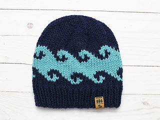 knit hat with intarsia waves on white wooden background