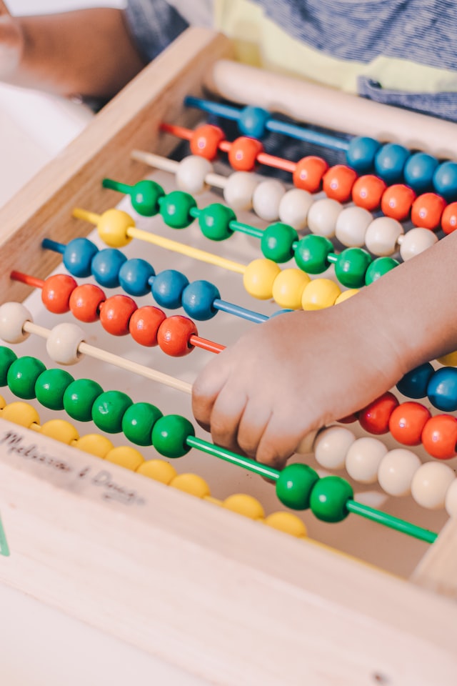 A child plays with an abacus or wooden counting tool to strengthen their number sense skills.